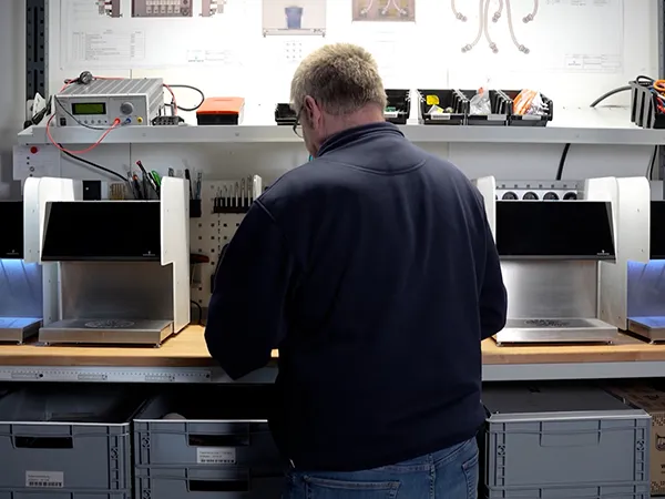 Mitarbeiter bei der Montage zwischen zwei Cocktail Booster Mini an der Werkbank